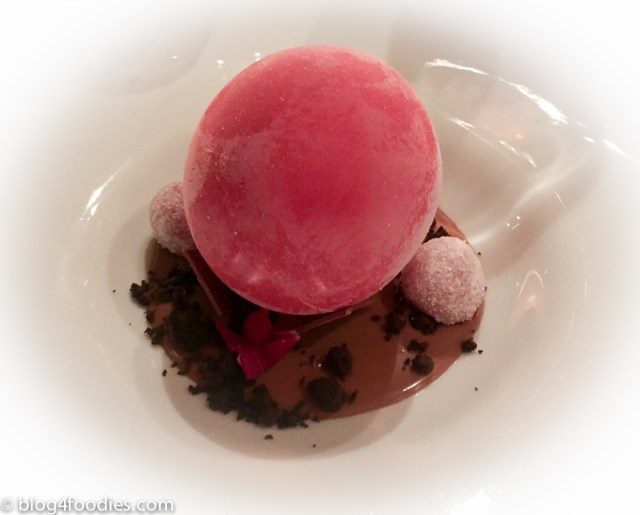Iced sphere of red fruit on tea cream with crystallized raspberries